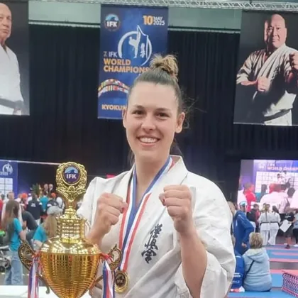 Angela Felber in her karate gi with her IFK World Championship medal and trophy