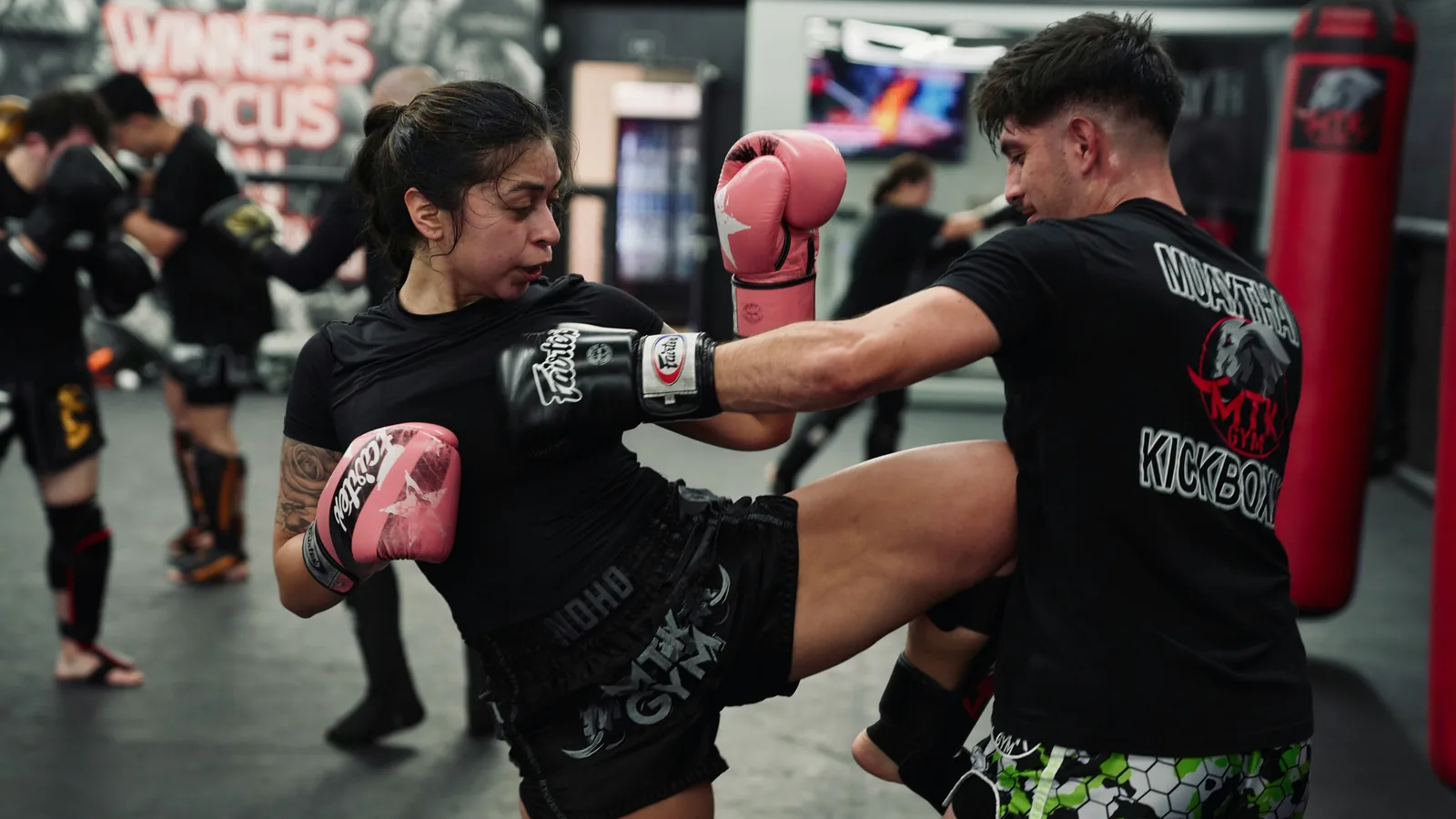 Athlete throwing a knee while sparring in a Muay Thai gym
